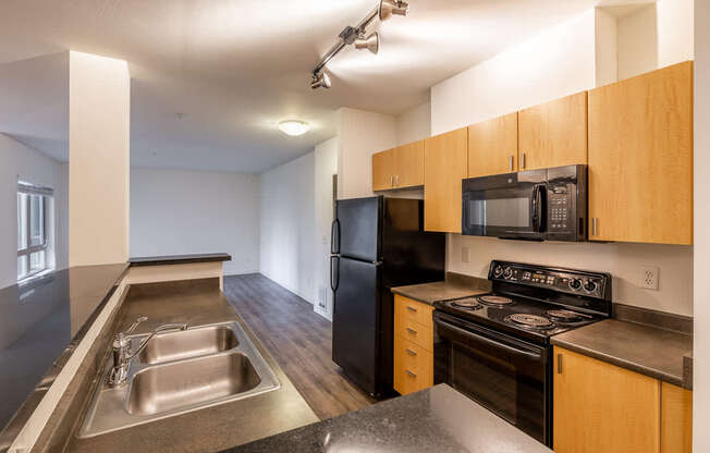 A kitchen with a black refrigerator, black stove, and black microwave.