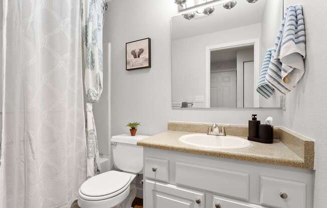 A white bathroom with a toilet, sink, and mirror.