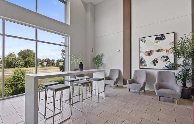 a bar with stools and chairs in a room with large windows