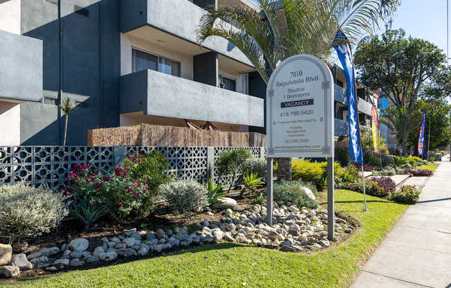 a sign in front of a building with palm trees