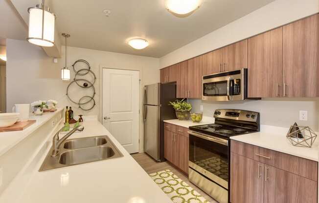 Model Kitchen with Sinks, Wood Inspired Floor, Sinks, Countertop, Oven, Wood Cabinets, Ceiling Lights