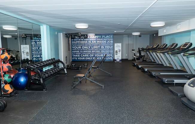 a large fitness room with cardio equipment and a motivational quote on the wall