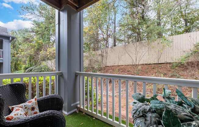 A chair with a pillow is on a porch.