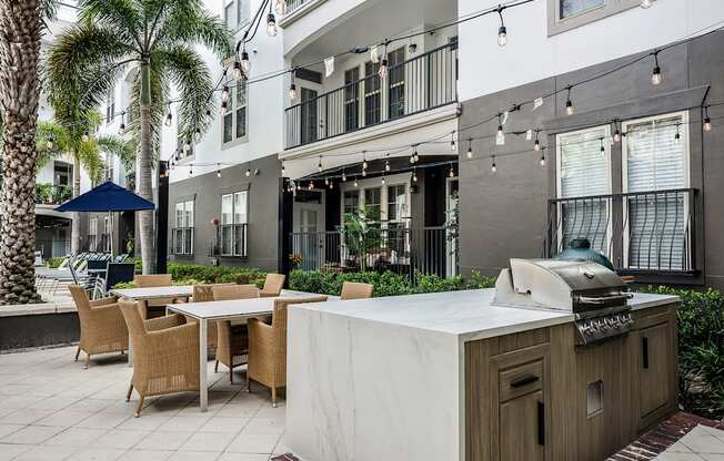 A patio with a table, chairs, and a grill.