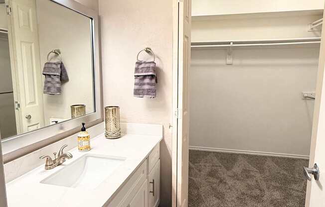 A bathroom with a sink, mirror, and towel rack.