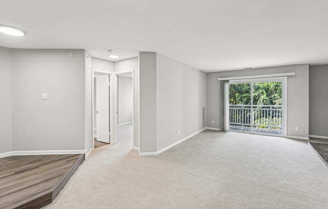 A spacious room with a carpeted floor and a balcony with a railing.