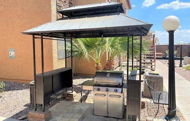 A patio with a grill and a table under a roof.