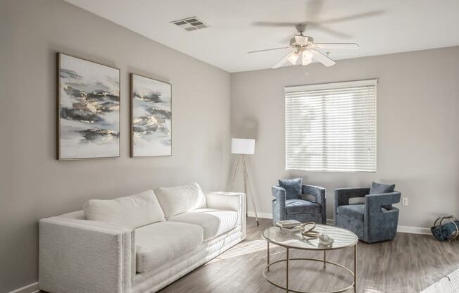 a living room with a white couch and a ceiling fan