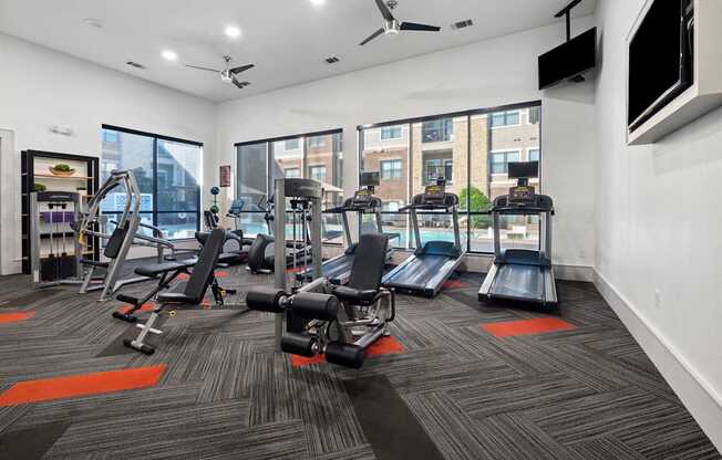 A gym with a variety of equipment including treadmills, weights, and exercise machines.