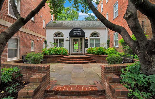 A brick pathway leads to a white building with a black sign that says "Leasing Center.".