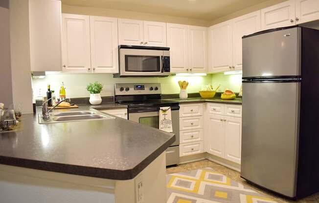 A modern kitchen with a black refrigerator and white cabinets.