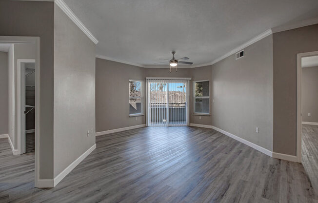a living room with a ceiling fan and a door to a balcony