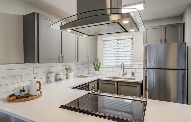 A modern kitchen with a stainless steel refrigerator and a large island with a sink.
