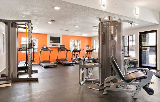 A gym with orange walls and a variety of equipment.