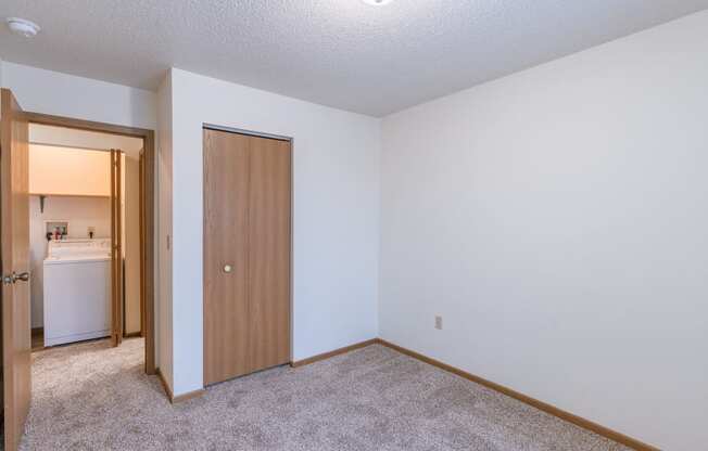 a bedroom with a door to a hallway. Fargo, ND Country Edge Apartments