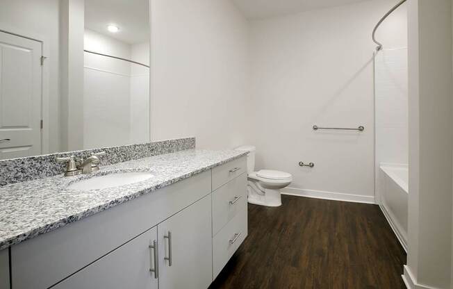 A bathroom with a toilet, sink, and a bathtub with a shower head.
