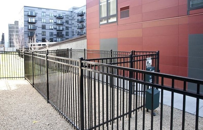 A black metal fence in front of a red building.