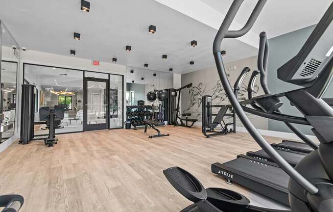 A gym with a variety of equipment including treadmills and weights.