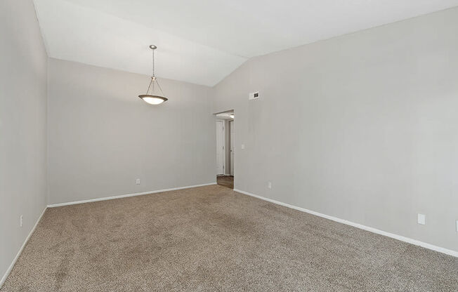 an empty living room with carpet and a door to a hallway
