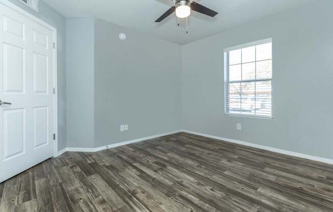 A room with a ceiling fan and a window with blinds.