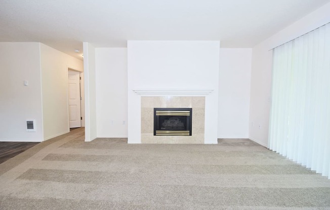 an empty living room with a fireplace and a carpet