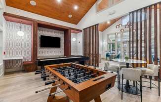 A shiny pool table is in the middle of a room with a bar and a television.