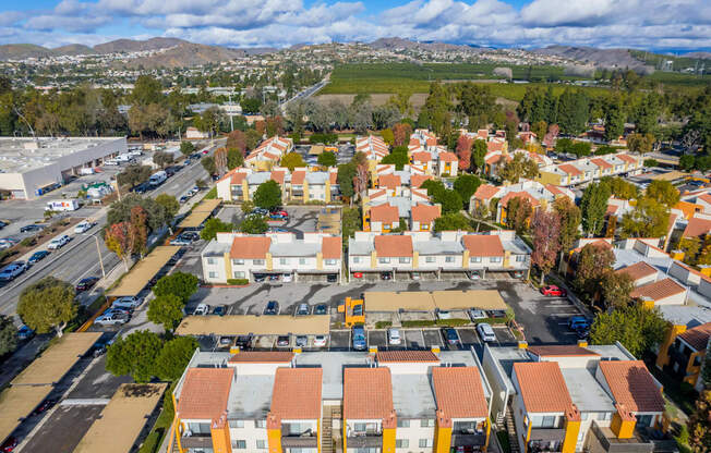 an aerial view of a neighborhood with orange roofs and a green field in the background