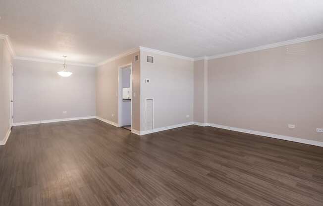 an empty living room with wood flooring and white walls