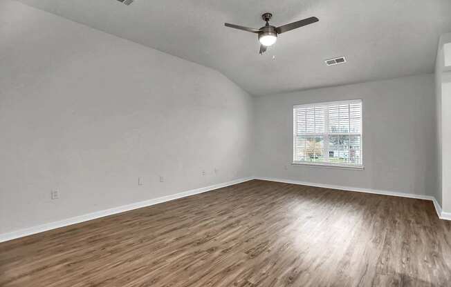 an empty living room with hardwood floors and a ceiling fan