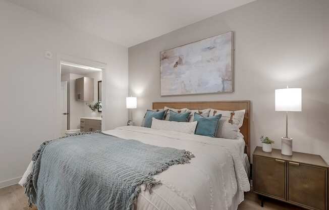 A bedroom with a large bed and a painting on the wall.