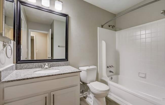 a bathroom with sink and toilet and white shower with soaking tub at Veridian at Sandy Springs apartments
