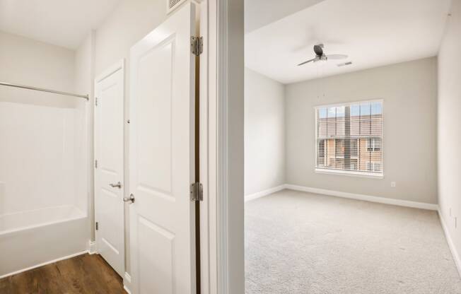 an empty bedroom with white doors and a window