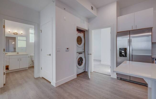 A modern kitchen with white cabinets and a wooden floor.