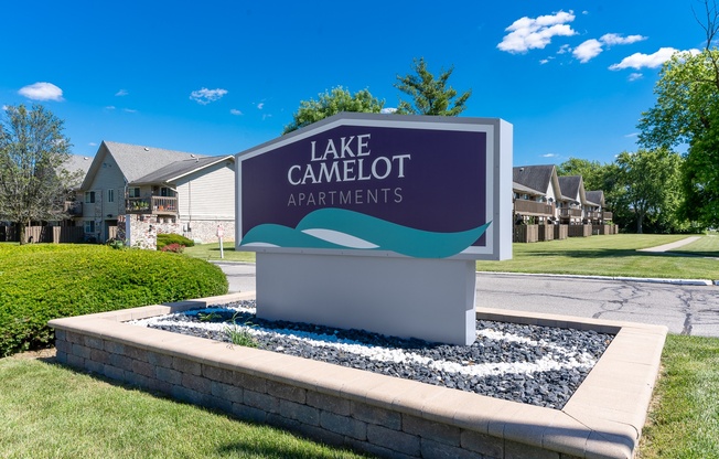a sign that reads lake camoult apartments in front of a street with houses