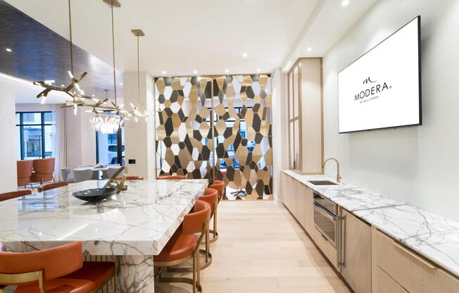 A stylish catering kitchen at Modera Liberty Row offers ample prep space, marble surfaces, and seating designed for hosting and everyday convenience.