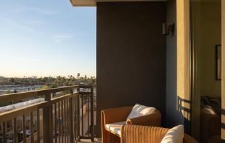 A private balcony retreat with woven seating and sunset views—your own outdoor escape above the city.