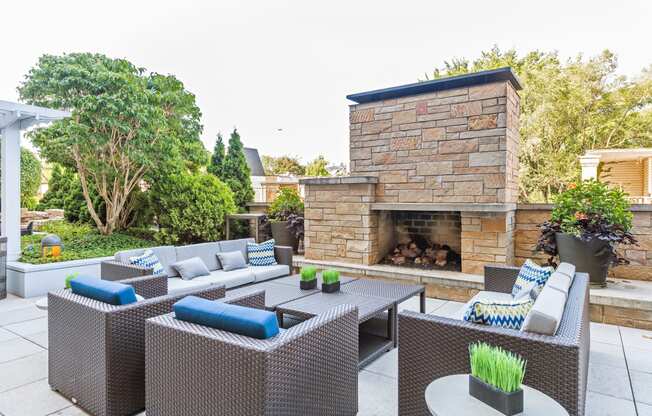 a patio with wicker furniture and a stone fireplace