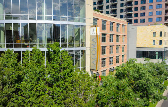 A modern building with a glass facade is surrounded by trees.