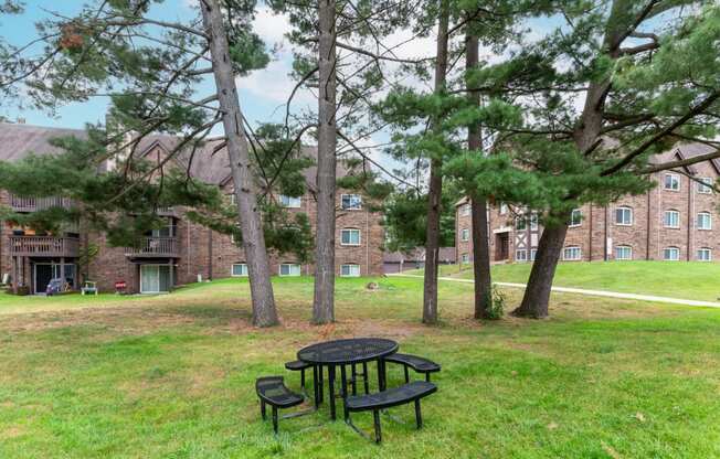 a picnic table in the grass in front of a brick building