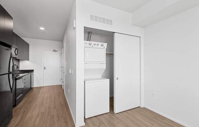 A kitchen with a refrigerator, oven, and a white door leading to a pantry.
