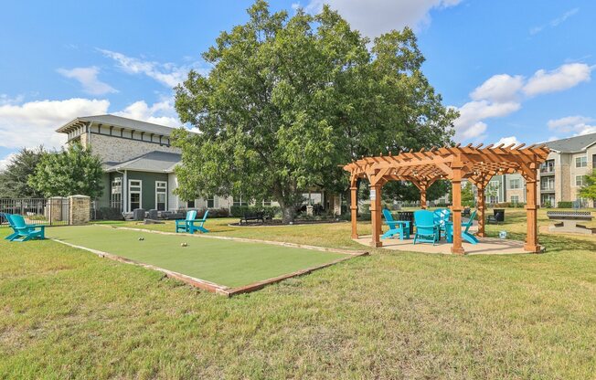 A sunny day at the park with a shuffleboard court and a pergola.