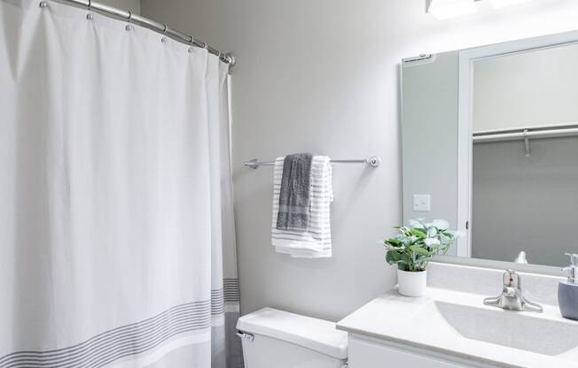 a bathroom with a white sink and toilet and a white shower curtain