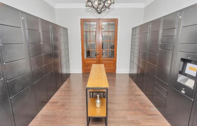 Mail room for package pick up with hanging chandelier, slender table in the middle and double doors