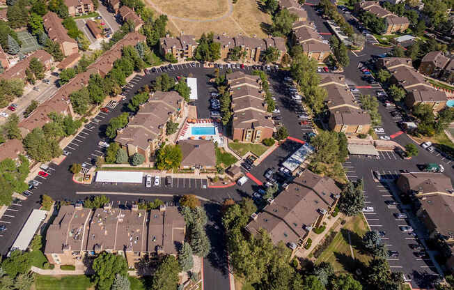 A bird's eye view of a residential area with houses, roads, and a swimming pool.