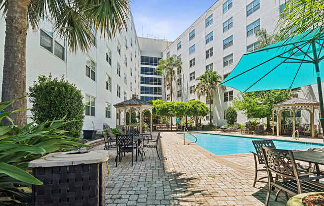 A pool area with a table and chairs and umbrellas.