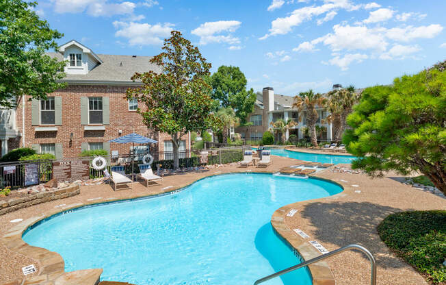 A swimming pool surrounded by trees and chairs.