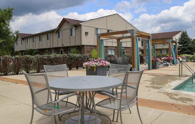 a patio with a table and chairs next to a swimming pool at Village Club of Rochester Hills, Shelby Township Michigan