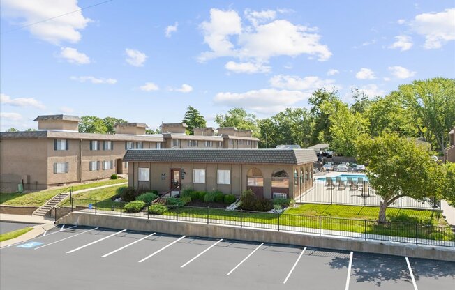 A parking lot in front of a building with a pool.