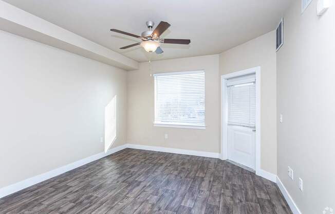 A room with a ceiling fan and wooden flooring.