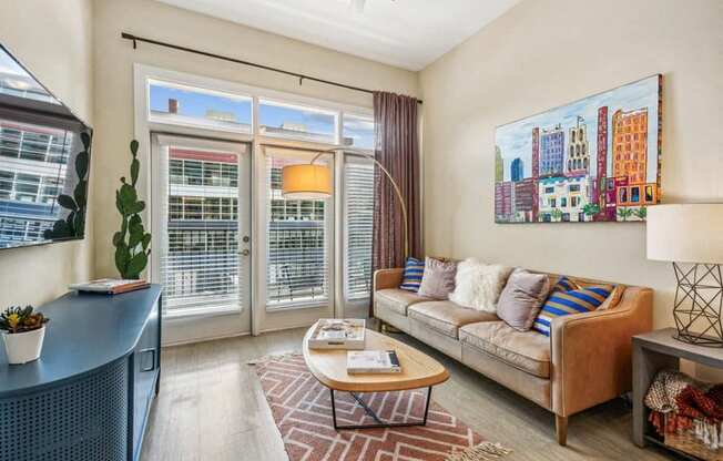 a living room with a couch and a tv and sliding glass doors at Link Apartments Innovation Quarter, North Carolina